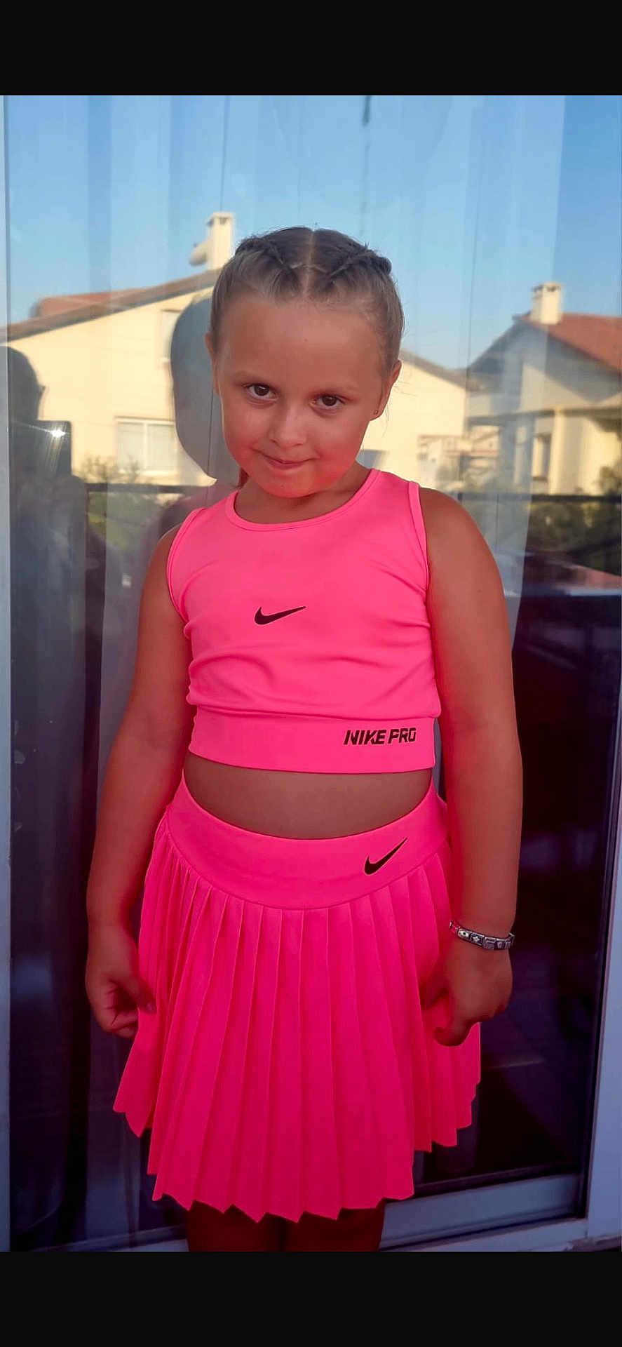 Gracie-Mae joined the competition — help win amazing prizes! child, girl, pink_outfit, nike, braided_hair, smile, pose, daylight, glass_door, reflection, bracelet, pleated_skirt, tank_top, outdoor, fashion, portrait, happy, cute, person, casual