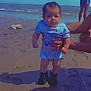 Kamari joined the competition — help win amazing prizes! baby, beach, ocean, sand, person, blue_sky, dinosaur_onesie, black_boots, shadow, hand, tattoo, footwear, child, outdoor, summer, waves, water, casual_clothing, standing, sunlight