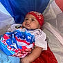 baby, flag, puerto_rico, headband, shirt, red, blue, white, infant, clothing, portrait, child, cute, resting, indoors, hand, face, expression, colorful, fabric