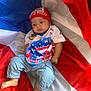 baby, child, flag, puerto_rico, headband, shirt, pants, barefoot, fabric, red, blue, white, portrait, infant, clothing, person, sitting, indoors, cute, expression