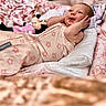 baby, infant, smile, blanket, onesie, plush_toy, minnie_mouse, face, hands, cute, lying_down, soft_texture, patterned_clothing, child, indoor, portrait, expression, happy, cozy, toddler