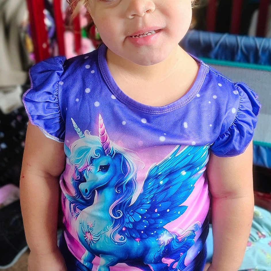 Lilyann is registered to the contest to win money with this photo: baby, blonde, clothing, costume, crib, cushion, dress, face, furniture, hair, head, homedecor, indoors, infantbed, pants, person, photography, portrait, purple, t_shirt