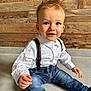 toddler, child, boy, blue_eyes, white_shirt, suspenders, jeans, sitting, floor, wooden_wall, indoor, portrait, cute, smiling, happy, casual_clothing, young_child, fashion, hair, person