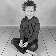 Brody joined the competition — help win amazing prizes! child, smiling, curly_hair, sitting, cross_legged, hoodie, jeans, barefoot, studio, black_and_white, floor, wooden_floor, portrait, happy, young, kid, casual_clothing, cute, innocence, joy