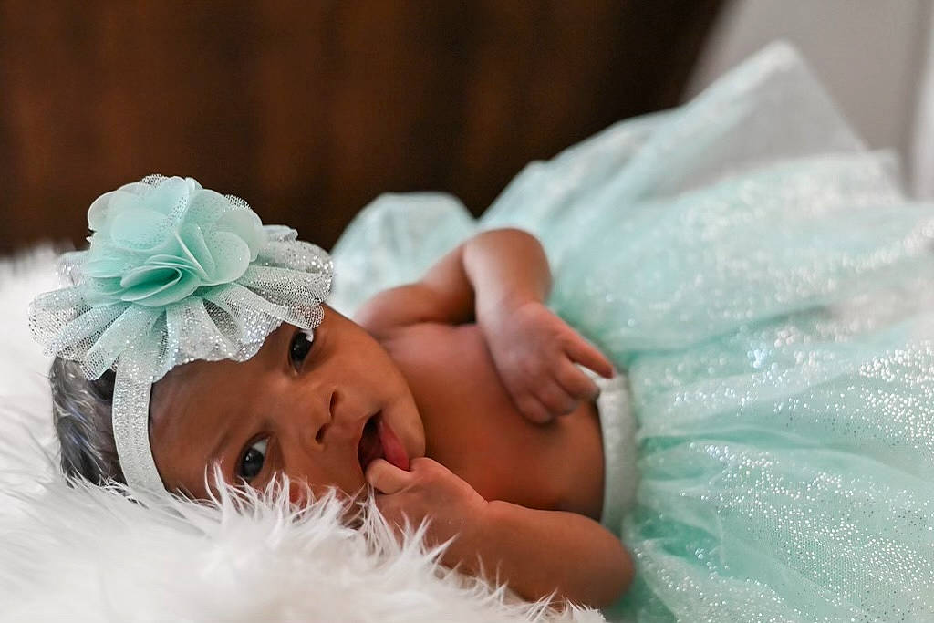 Ava is registered to the contest to win money with this photo: baby, bridal_accessory, bridal_clothing, dress, eyebrow, eyelash, finger, flower, gesture, grass, hand, happy, headband, headpiece, headwear, linens, person, petal, skin, textile