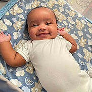 Kevin is registered to the contest to win money with this photo: baby, smiling, blanket, bear_pattern, cloud_pattern, onesie, playpen, infant, cute, happy, lying_down, child, soft_texture, indoors, portrait, face, head, arms, cozy, comfort