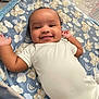 baby, smiling, blanket, bear_pattern, cloud_pattern, onesie, playpen, infant, cute, happy, lying_down, child, soft_texture, indoors, portrait, face, head, arms, cozy, comfort