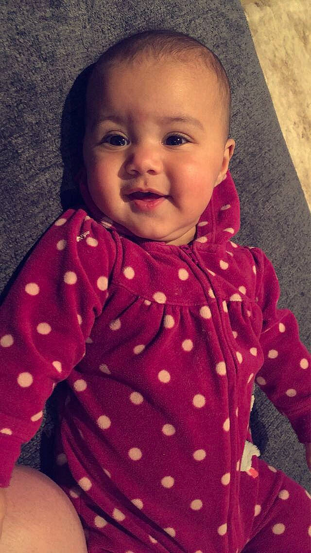 Melody is registered to the contest to win money with this photo: arm, baby_toddler_clothing, cheek, chin, dress, eyebrow, facial_expression, human_body, lip, mouth, nose, orange, organ, outerwear, person, pink, product, purple, skin, sleeve