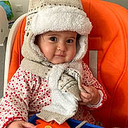 Anne-Laure a rejoint le concours — aidez-le/la à gagner de superbes lots ! baby, cheeks, child, colorful, curious, cute, face, hand, hat, indoor, infant, knitted, orange_high_chair, person, play, scarf, seated, smile, toy, warm_clothing