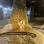 dog, chihuahua, sculpture, bench, night, urban, street, light, small_dog, metal, texture, outdoor, animal, pet, art, curious, shiny, building, sidewalk, lonely