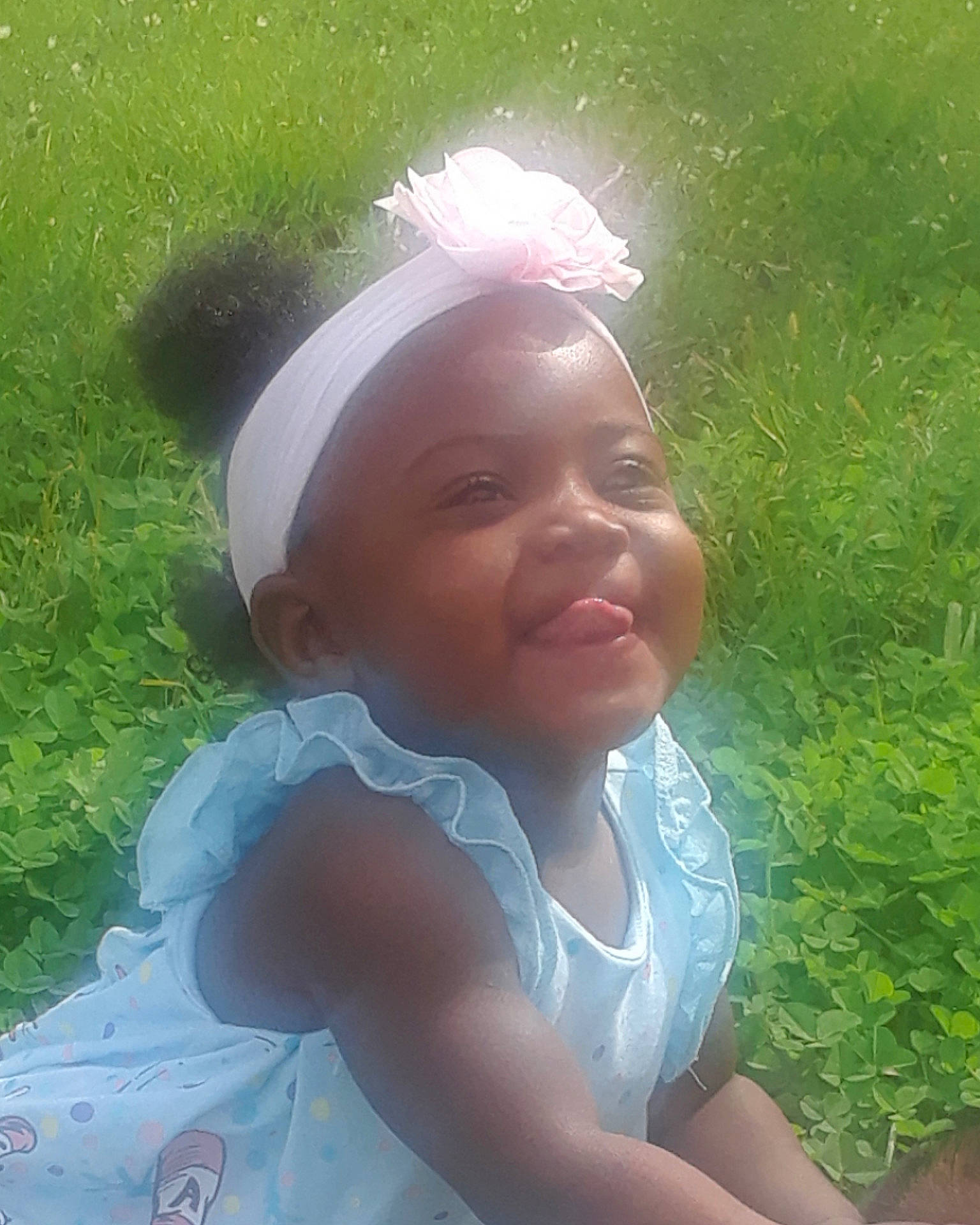 Taylin is registered to the contest to win money with this photo: cheek, child, day, emotion, face, facial_expression, fun, girl, grass, hair, hair_accessory, head, headgear, headpiece, human_hair_color, infant, nose, person, pink, skin