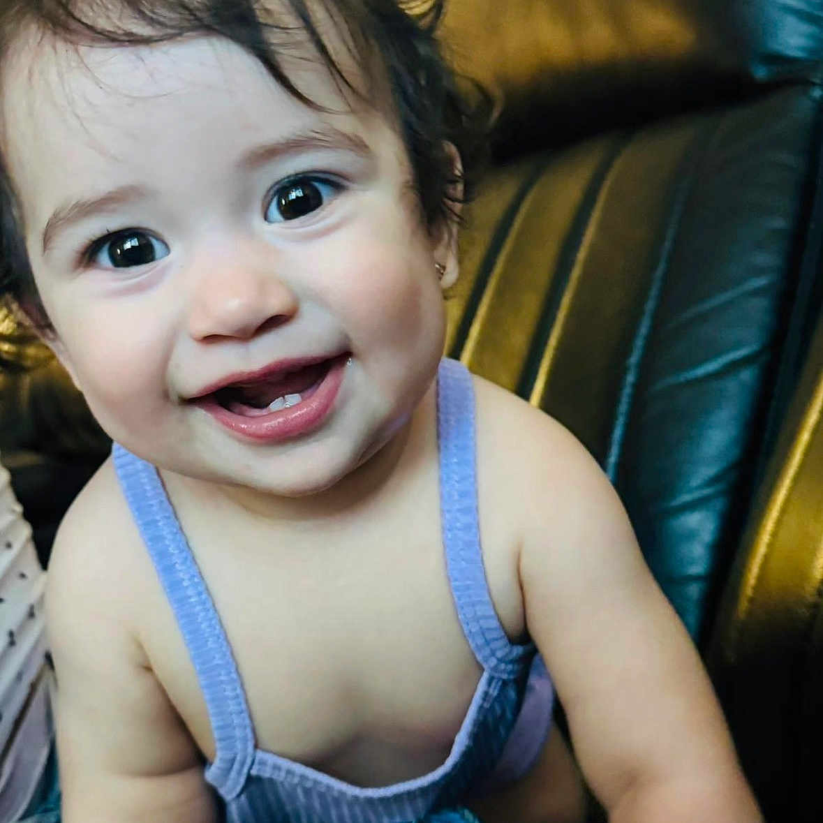 Ailany Hernández is registered to the contest to win money with this photo: arm, baby, child, clothing, couch, cute, eyes, face, hair, happy, indoors, leather, person, portrait, purple, sitting, skin, smile, teeth, young
