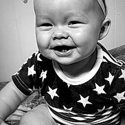 Autumn is registered to the contest to win money with this photo: baby, smiling, face, headband, bow, stars, clothing, infant, cheeks, teeth, black_and_white, indoor, cute, happy, person, closeup, sitting, arm, mouth, portrait