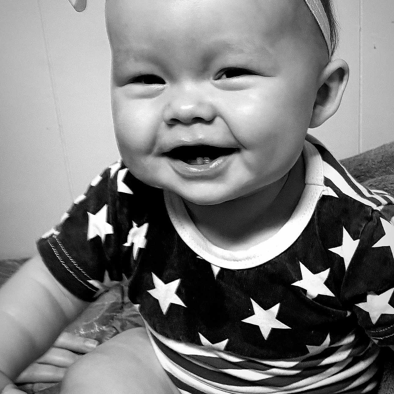 Autumn is registered to the contest to win money with this photo: arm, baby, black_and_white, bow, cheeks, closeup, clothing, cute, face, happy, headband, indoor, infant, mouth, person, portrait, sitting, smiling, stars, teeth