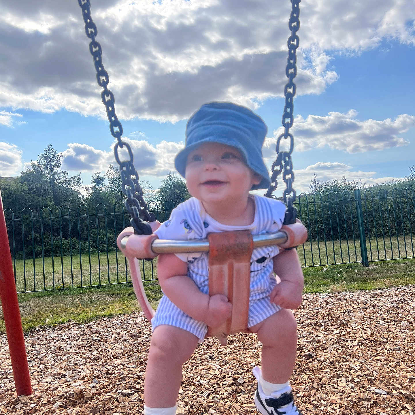 Tommy joined the competition — help win amazing prizes! blue_sky, child, clouds, daylight, fence, fun, grass, happy, hat, outdoor, person, playground, romper, shoes, smiling, socks, summer, swing, toddler, wood_chips