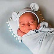 Jakhari is registered to the contest to win money with this photo: newborn, baby, sleeping, swaddled, blanket, hat, bear_ears, cushion, pom_pom, soft_texture, peaceful, infant, portrait, indoors, cute, resting, child, wrapped, cozy, head