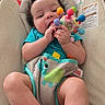 Natalia joined the competition — help win amazing prizes! baby, infant, toy, colorful, seat, chewing, cute, child, indoors, clothing, blue_shirt, playful, happy, person, young_child, comfort, bright, patterned, dinosaur_print, closeup