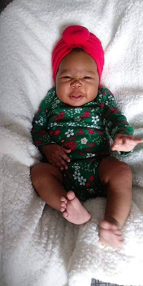 Zola Kimberlynn is registered to the contest to win money with this photo: arm, baby, baby_toddler_clothing, cap, child, comfort, face, facial_expression, finger, hand, headwear, lap, leg, linens, mouth, person, pink, skin, sleeve, smile