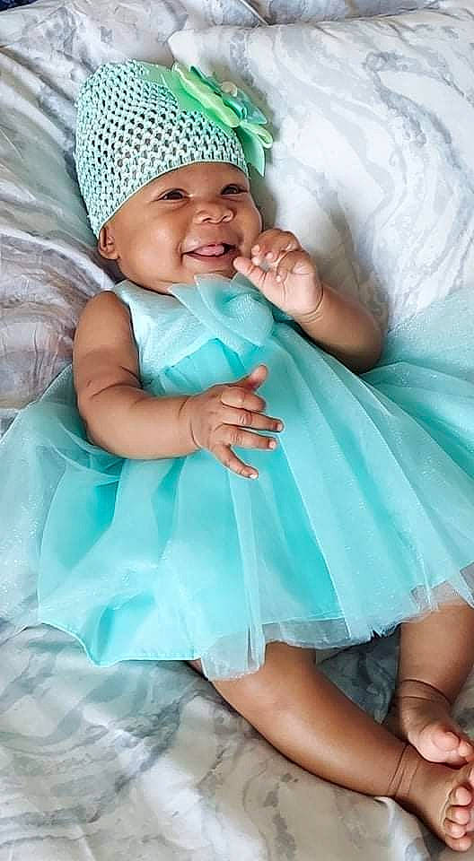 Zola Kimberlynn is registered to the contest to win money with this photo: aqua, baby, baby_toddler_clothing, cap, comfort, dress, face, facial_expression, finger, fun, gesture, green, happy, headgear, headwear, organ, person, photograph, pink, skin