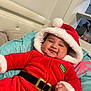 Angel joined the competition — help win amazing prizes! baby, child, smiling, red_clothing, santa_hat, holiday_outfit, plush, cushion, indoor, cute, happy, face, person, christmas, festive, infant, cozy, holiday, seat, apparel