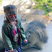 Lana joined the competition — help win amazing prizes! child, face_paint, girl, smiling, zoo, lioness, animal, glass, enclosure, rocks, grass, map, jacket, dress, shoes, daylight, nature, happy, portrait, wildlife