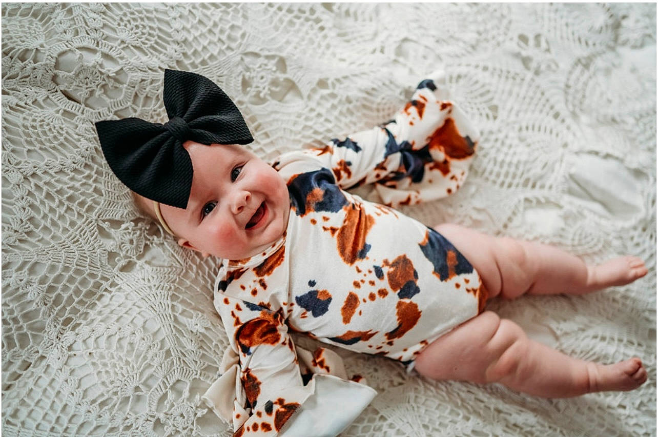 Navy is registered to the contest to win money with this photo: baby, baby_toddler_clothing, cap, costume_hat, doll, dress, fawn, flooring, foot, happy, hat, headwear, human_leg, linens, mammal, outerwear, pattern, person, sleeve, sun_hat