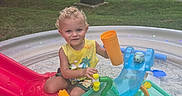 Cain joined the competition — help win amazing prizes! child, curly_hair, daylight, fun, grass, greenery, happy, nature, outdoor, plastic, play, pool, recreation, slide, summer, toddler, toy_cup, trees, water_toys, yellow_shirt
