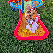 Cain joined the competition — help win amazing prizes! backyard, bowling_pins, child, curly_hair, daylight, fun, grass, happy, inflatable, inflatable_toy, outdoor, play, recreation, shorts, splash, summer, toddler, toy, water_slide, yellow_shirt