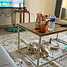 cats, two_cats, pet, furry, sleeping, relaxed, lying_down, living_room, coffee_table, rug, sofa, television, remote_control, water_bottle, snack, cup, toy, home, indoor, sunlight