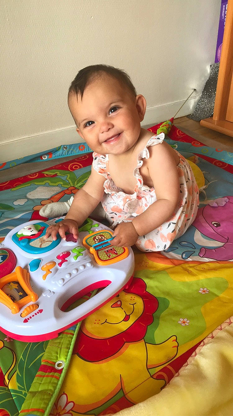 Miya participe au concours pour gagner de l'argent avec cette photo : baby, baby_playing_with_toys, baby_products, baby_toddler_clothing, child, event, flooring, fun, happy, joy, organ, person, picture_frame, pink, play, product, room, sitting, smile, toddler