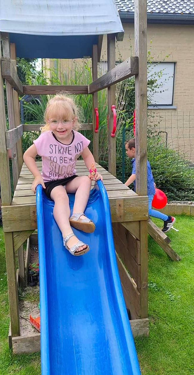 Maëlyne a rejoint le concours — aidez-le/la à gagner de superbes lots ! baby_toddler_clothing, child, chute, city, fun, grass, happy, joy, leisure, outdoor_play_equipment, people_in_nature, person, plant, play, playground, playground_slide, recreation, shorts, sitting, smile