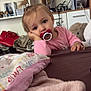 Cyanea participe au concours pour gagner de l'argent avec cette photo : toddler, child, pacifier, bed, blanket, toy, stuffed_animal, shelf, television, indoor, person, pink_clothing, bracelet, hair_tie, face, expression, furniture, living_room, decor, relaxed