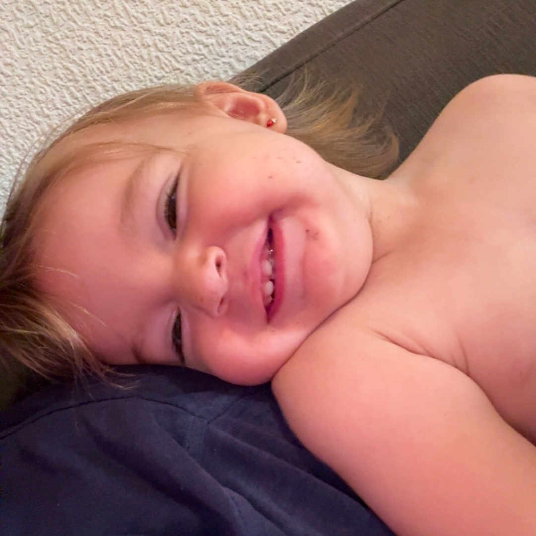 Cyanea a rejoint le concours — aidez-le/la à gagner de superbes lots ! casual, cheek, child, closeup, dark_cloth, earring, embroidery, fabric, face, hair, happy, lying_down, pink, relaxation, shoulder, skin, smiling, texture, toddler, wall