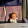 child, toddler, pacifier, seat, window, sunlight, hoodie, hair_tie, indoor, curious, purple_seat, table, daylight, person, young_child, hair, face, clothing, earrings, shadow