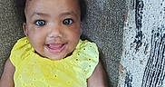 Alani Janae Herrod is registered to the contest to win money with this photo: arm, baby, child, couch, cute, eyebrows, eyes, face, hair_clip, happy, indoor, infant, pattern, person, portrait, seated, skin, smiling, texture, yellow_dress