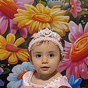 Dylani is registered to the contest to win money with this photo: child, baby, girl, portrait, headband, pink_dress, pearl_trim, floral_headband, flower_mural, colorful_background, big_flowers, eyes, face, smile, cheeks, indoor, photography, costume, cute, centered_subject