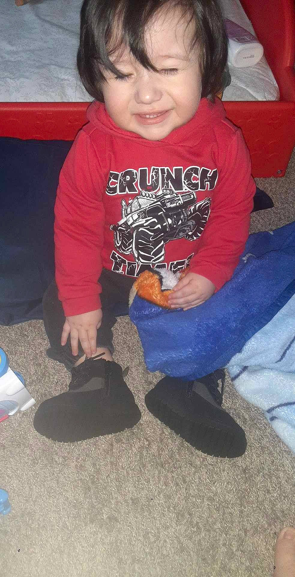 Mateo is registered to the contest to win money with this photo: baby_toddler_clothing, blue, clothing, elbow, electric_blue, flooring, fun, happy, human_leg, knee, lap, leg, mouth, person, sitting, sleeve, smile, sneakers, t_shirt, thigh