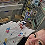 child, newborn, infant, adult, parent, hospital, nicu, incubator, ventilator, medical_equipment, blanket, duck_print, tubing, monitors, crib, swaddled, portrait, smile, caregiver, close_up