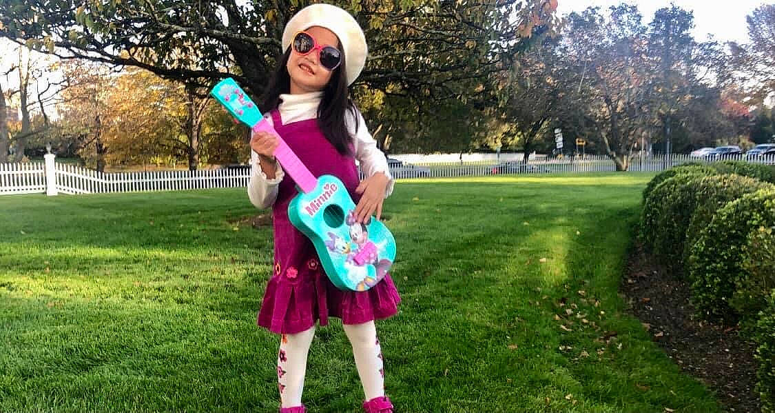 Zia is registered to the contest to win money with this photo: dress, eyewear, grass, grassland, guitar, happy, headwear, joy, leisure, meadow, musical_instrument, people_in_nature, person, pink, plant, street_fashion, sunglasses, t_shirt, toy, tree
