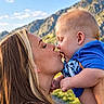 Dallas is registered to the contest to win money with this photo: baby, mother, child, kiss, portrait, outdoor, mountains, landscape, family, parenting, infant, blue_shirt, smiling, affection, sunlight, nature, sky, close_up, 抱抱, travel