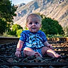 baby, child, infant, portrait, sitting, outdoor, mountains, mountain_view, railway_track, railroad, rocks, nature, landscape, blue_shirt, clothing, shorts, looking_at_camera, wide_eyed, sunlight, trees