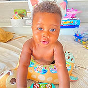 Iris a rejoint le concours — aidez-le/la à gagner de superbes lots ! baby, bright, cat_ears, child, colorful, curly_hair, cute, expression, face, giraffe_pillow, hands, indoor, infant, person, playroom, playtime, smiling, soft_toys, toy, young_child