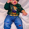 Kayden is registered to the contest to win money with this photo: child, baby, toddler, portrait, sitting, fashion, sunglasses, jewelry, sweater, jeans, sneakers, green, black, gold, curly_hair, fluffy_blanket, indoor, clothing, smiling, stylish