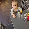 Maÿana a rejoint le concours — aidez-le/la à gagner de superbes lots ! toddler, child, table, indoor, floor, chair, bottle, salt_shaker, pepper_shaker, curious, person, hair_tie, clothing, flooring, hand, expression, furniture, kitchen, small_person, playing