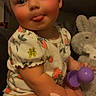 baby, child, clothing, cozy, cute, face, furniture, head, indoor, person, playful, plush_toy, purple_toy, rosy_cheeks, sitting, smile, soft_toy, strawberry_pattern, toddler, tongue_out