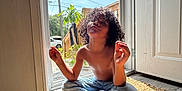 Kye is registered to the contest to win money with this photo: child, curly_hair, shirtless, jeans, sitting, rug, door, open_door, sunlight, shadow, indoor, outdoor, plant, sky, wood_floor, peaceful, relaxed, portrait, home, daylight