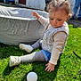 toddler, child, grass, ball, outdoor, sunlight, playing, pigtails, shoes, vest, long_sleeve_shirt, shorts, fabric_pool, adults, legs, garden, greenery, daylight, curious, sitting