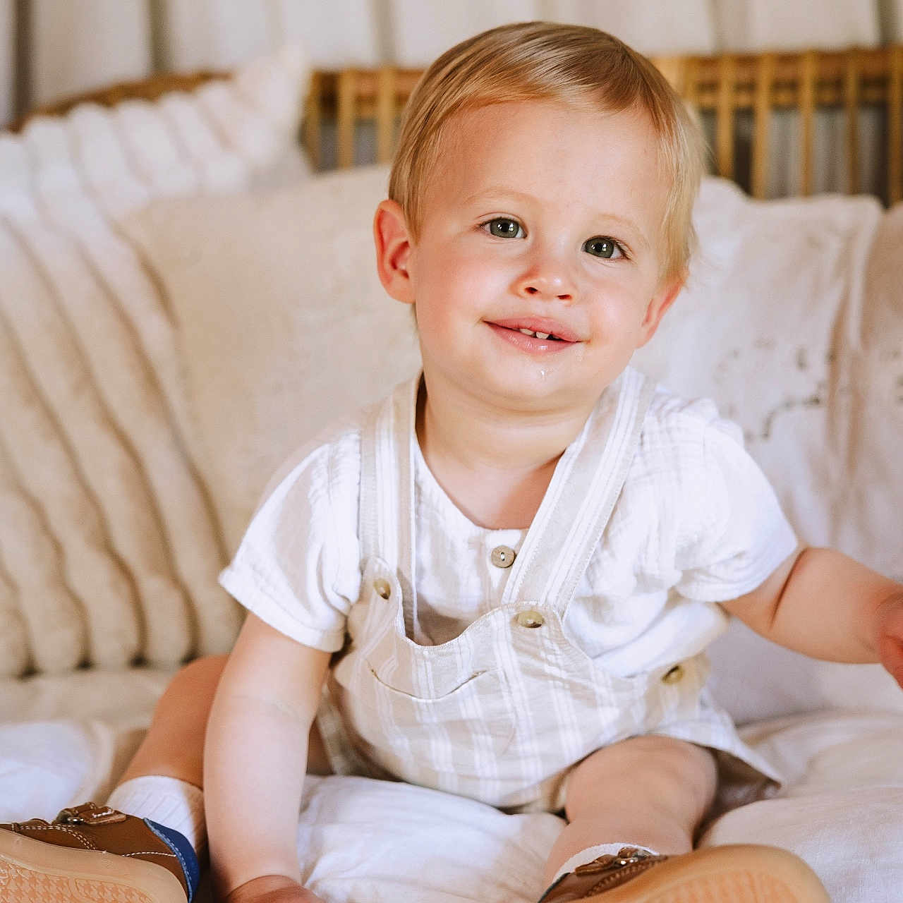 Noah participe au concours pour gagner de l'argent avec cette photo : baby, brown_shoes, casual, child, cushions, cute, face, happy, home, indoor, overalls, person, portrait, sitting, smiling, soft_light, toddler, white_clothing, wicker_bench, young_child