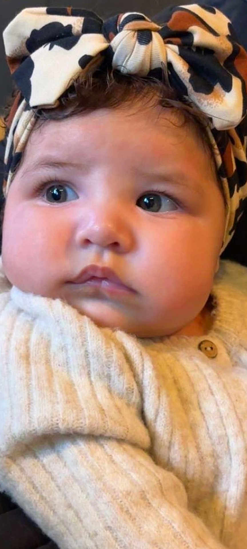 Insiyah participe au concours pour gagner de l'argent avec cette photo : baby, infant, child, face, headband, bow, curly_hair, sweater, cozy, cute, closeup, portrait, indoor, skin, eyelashes, button, fashion, headwear, looking_away, soft_lighting