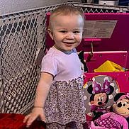 Isley joined the competition — help win amazing prizes! toddler, child, toy, stuffed_animal, play_area, pink, minnie_mouse, smile, clothing, indoor, face, person, furniture, blanket, plush, happy, standing, home, cute, young_child